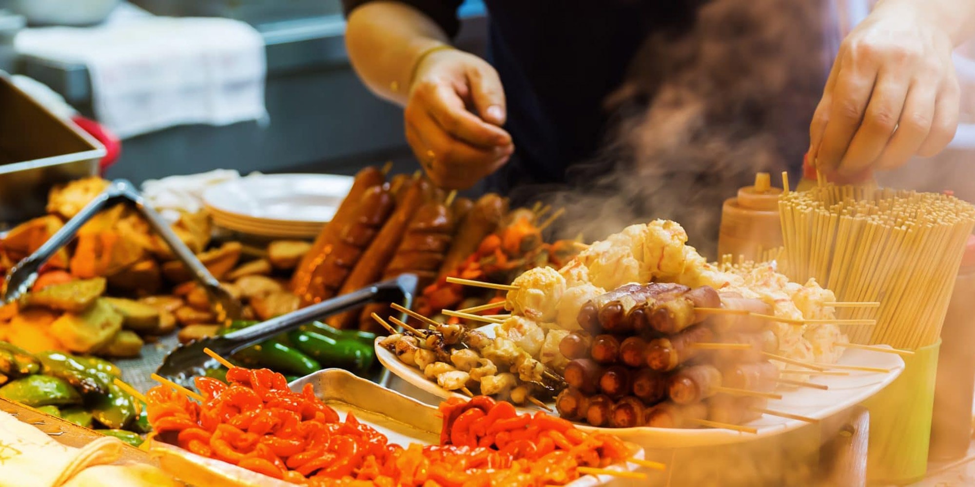 Thai street-food skewers and grilled snacks being prepared at a Krabi market